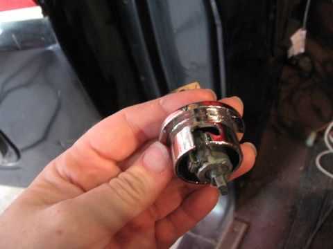 1966 Ford F-100 - A person holds a detached chrome door lock cylinder, likely for a vehicle repair or replacement.