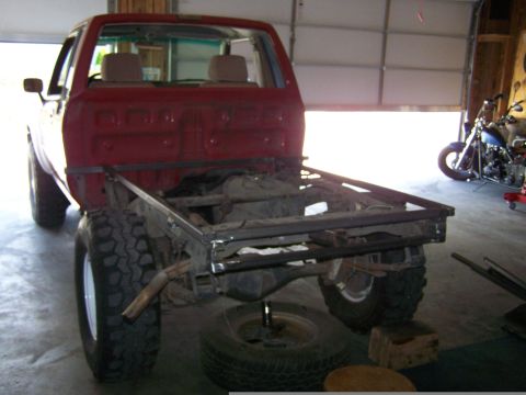 1988 Suzuki Samurai - A red pickup truck chassis is being worked on in a garage, with a motorcycle visible in the background.