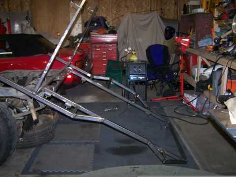 1988 Suzuki Samurai - A metal frame structure is being worked on in a garage, with a red car visible in the background.