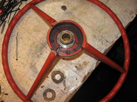 1966 Ford F-100 - A red steering wheel is shown disassembled on a workbench, with various parts and tools scattered around.