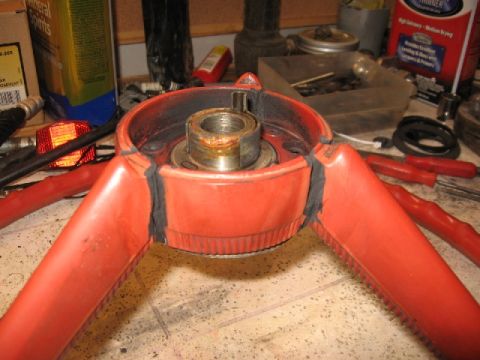 1966 Ford F-100 - Close-up of a red steering wheel component, showing the central hub and metal shaft, likely undergoing restoration.