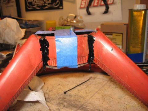 1966 Ford F-100 - A red plastic component is being repaired with black adhesive and blue tape on a cluttered workbench.