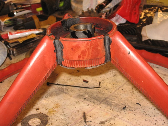 Red tubular metal part with central hub on a workbench