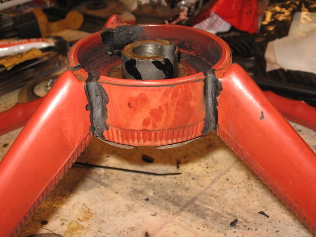 Close-up of a red steering wheel hub with black tape and a metal shaft