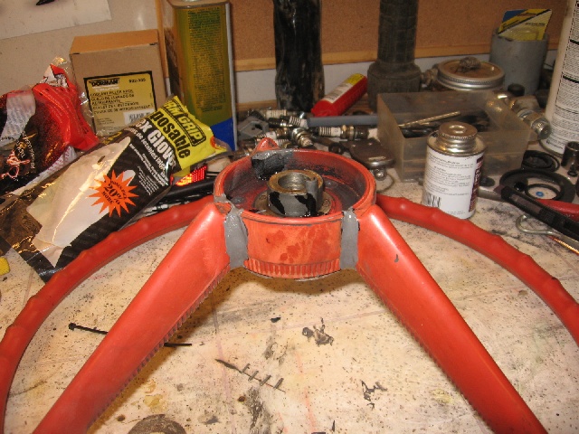 Red vintage steering wheel face-down on a workbench during hub work