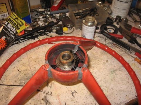 1966 Ford F-100 - A red steering wheel is disassembled on a workbench, surrounded by various tools and automotive parts.