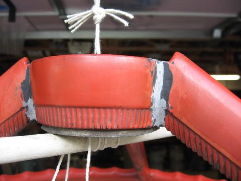1966 Ford F-100 - Close-up of a red steering wheel hub showing repairs and ribbed texture, suspended by rope.