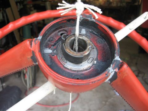 1966 Ford F-100 - Close-up of a red steering wheel hub, showing wear and tear, with a string attached for restoration purposes.