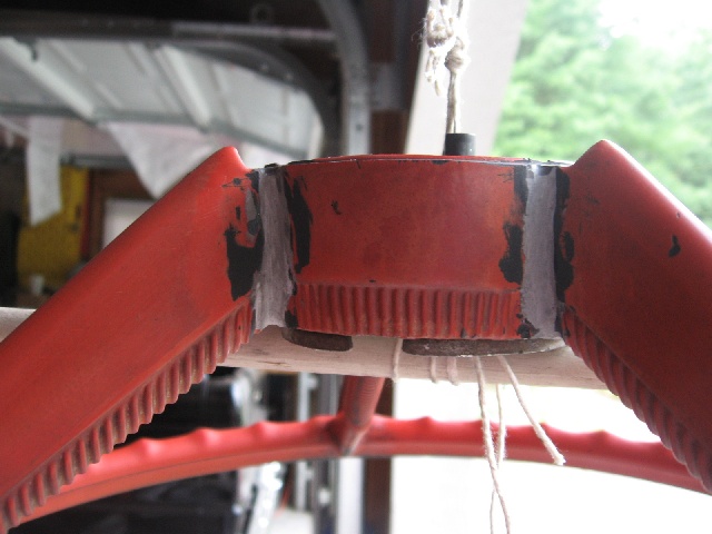 Close-up of a red steering wheel hub with visible wear and some white tape