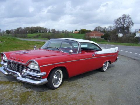1991 Ford Crown Victoria - A classic red and white 1957 Dodge Custom Royal Lancer coupe is parked on the side of a road with a scenic background.