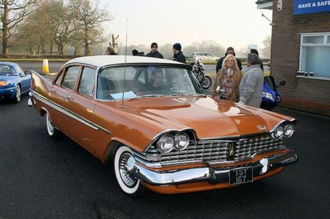 1991 Ford Crown Victoria - A classic orange 1959 Plymouth Belvedere sedan is parked outdoors with other vehicles and people around.