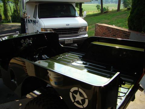 1948 Jeep Wrangler - A black Jeep CJ-series with a white star emblem is parked in front of a white RV.