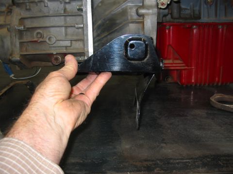 1993 Ford Taurus - A person holds a transmission mounting bracket near engine components.