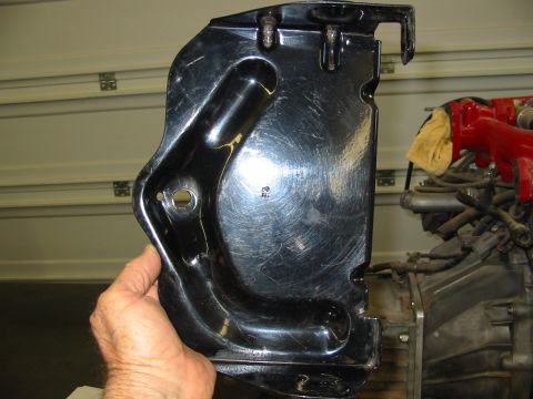 1993 Ford Taurus - A black metal bracket is held by a hand, with engine components visible in the background. The registry claims it is from a 1993 Ford Tauru…