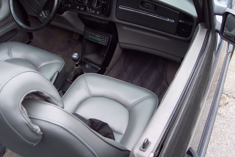 2001 Ford Crown Victoria - The interior of a car shows gray leather seats and a dashboard with a car stereo and climate controls.