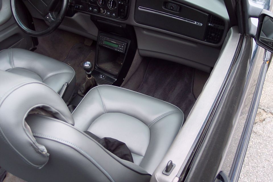Interior of a car with gray leather seats, a manual transmission, and a car stereo