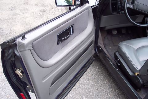 2001 Ford Crown Victoria - Interior view of a car's door panel and seat, with the door ajar.