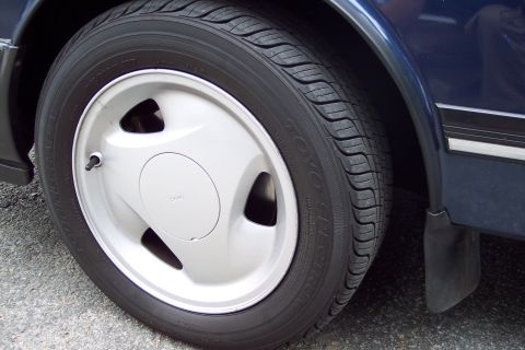 2001 Ford Crown Victoria - A close-up view of a silver wheel and tire on a dark blue vehicle, with visible tire brand text.