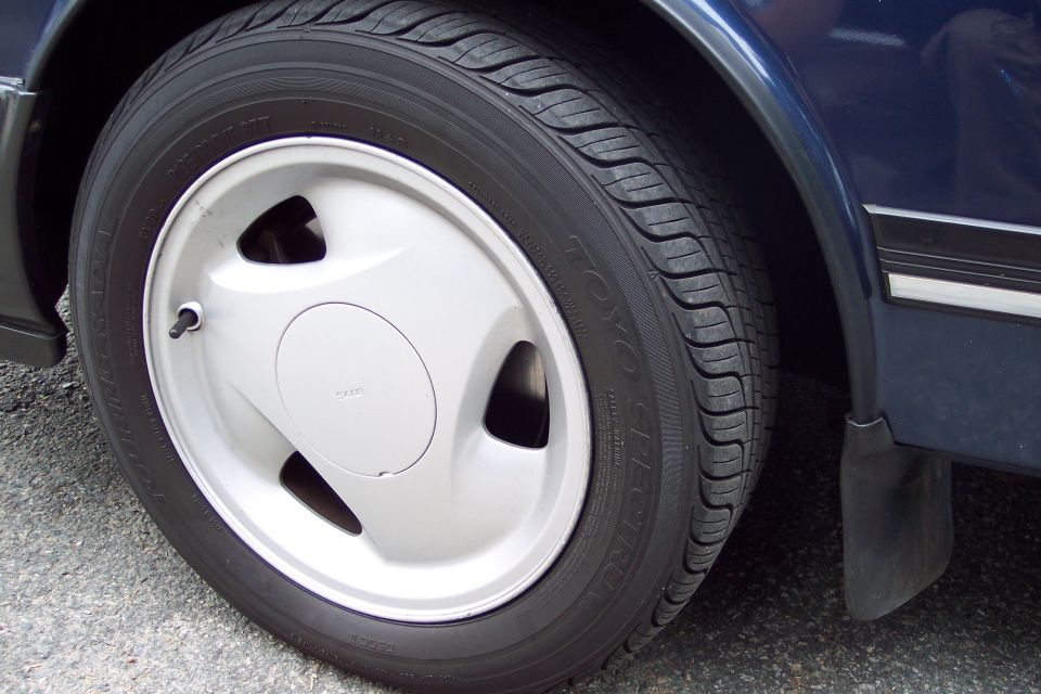 Close-up of a silver wheel with a TOYO tire on a dark blue car