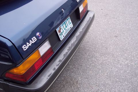 2001 Ford Crown Victoria - The rear of a dark blue Saab 900 is visible, showing the taillight, bumper, and a license plate.