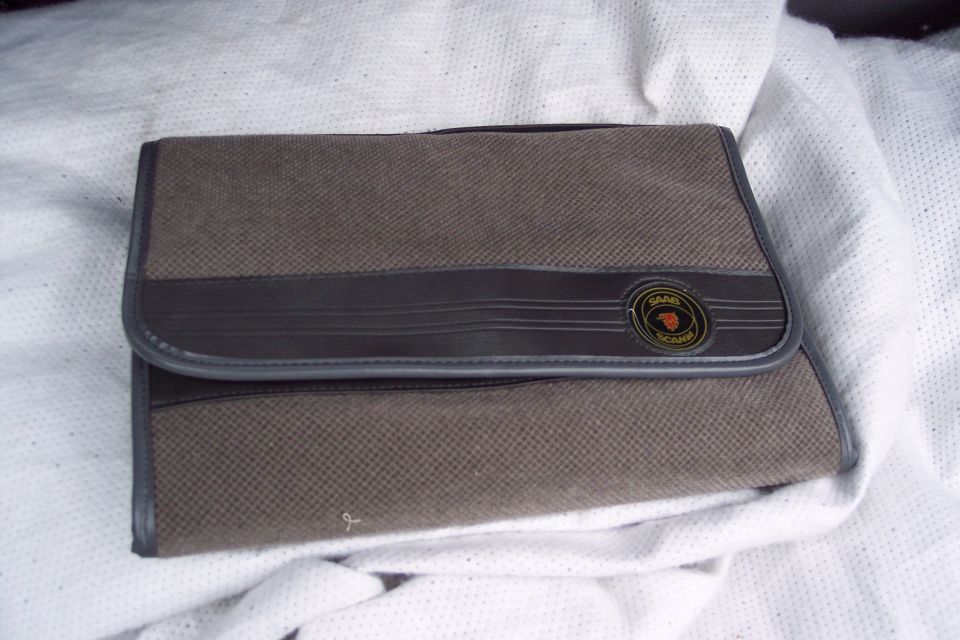 Brown fabric case with dark brown trim and a circular Saab logo badge