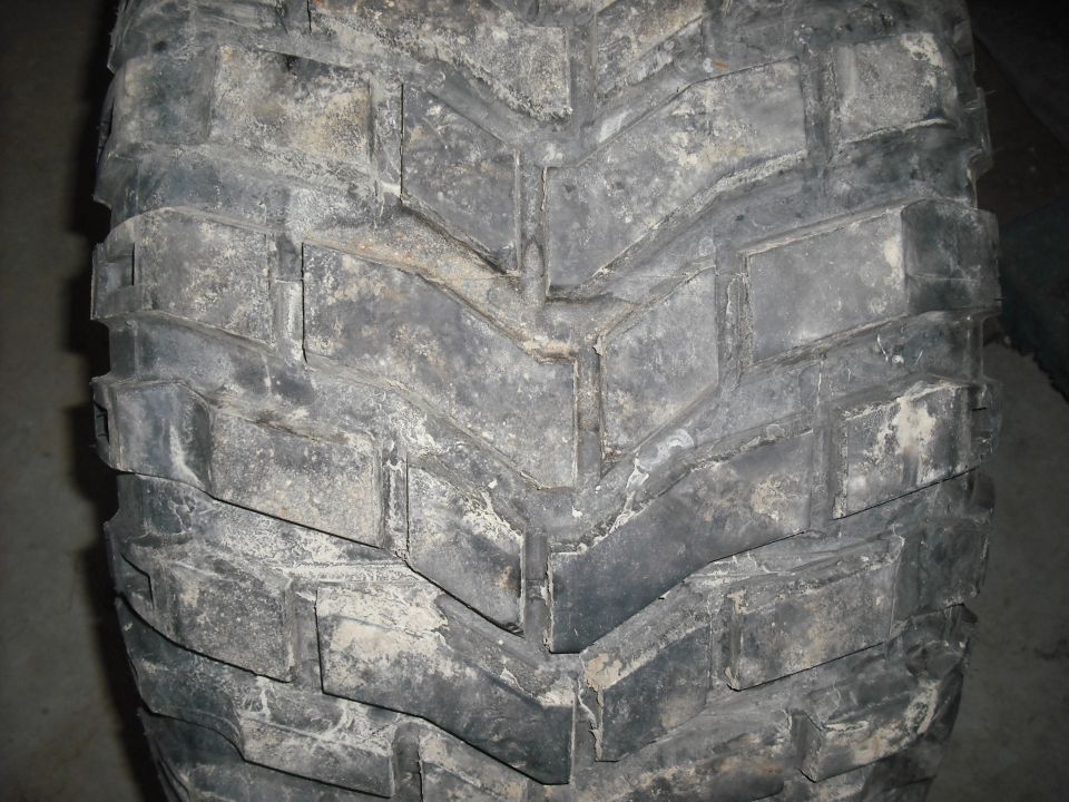 Close-up of a dirty, off-road tire tread with large, blocky lugs