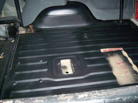 1985 Ford Bronco - The cargo area of a vehicle shows new black flooring with a piece of cardboard on the right side.