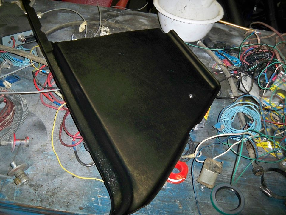 Black plastic trim piece on a workbench with wiring and tools