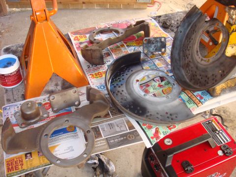 1992 Ford Bronco - Various brake components, including rotors and calipers, are arranged on newspapers alongside orange jack stands.