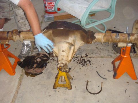1992 Ford Bronco - A differential axle assembly is shown supported by jack stands, with a person's hand visible.