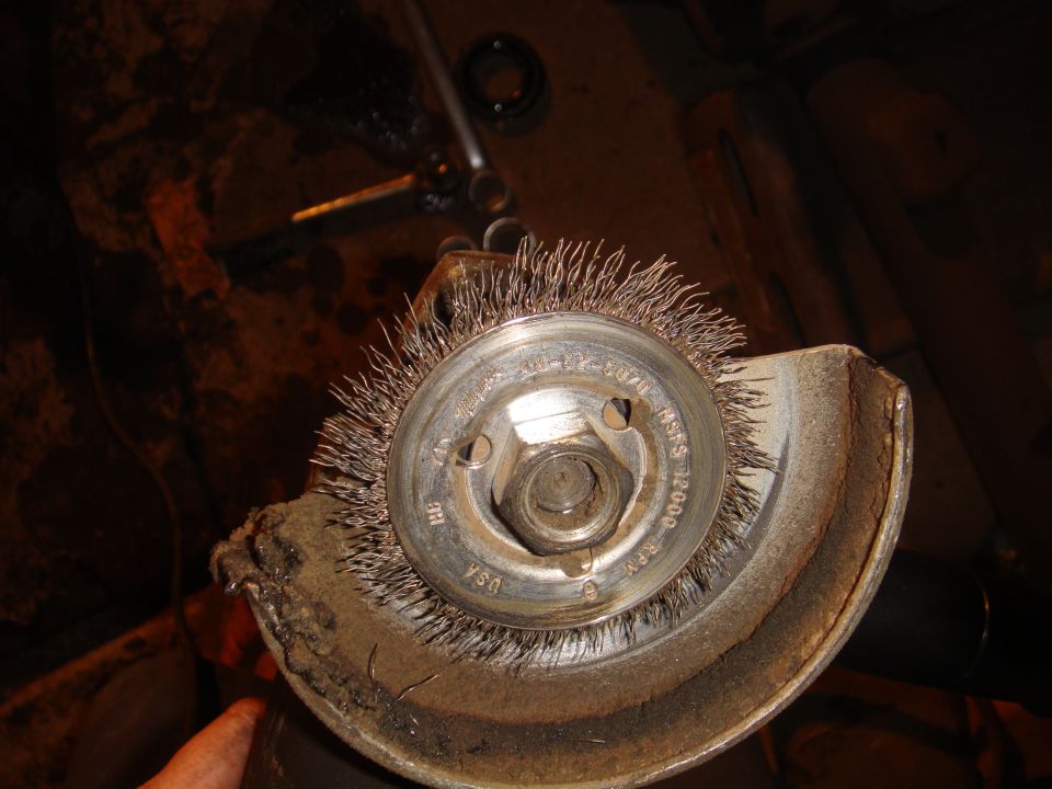 Wire wheel brush attached to an angle grinder, showing rust and wear