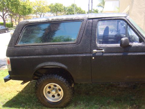 1992 Ford Bronco - This black Ford Bronco displays a textured paint job, visible from its side profile.