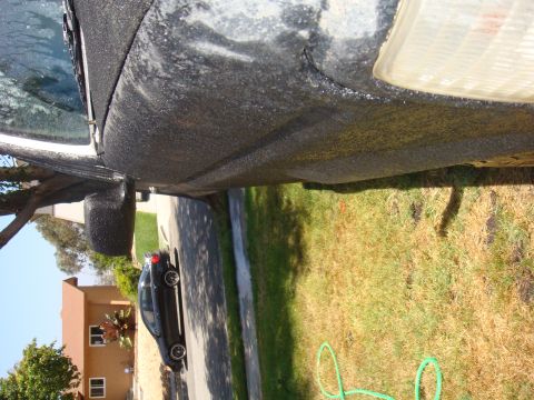 1992 Ford Bronco - Side view of a truck's fender and headlight, with a sedan visible in the background.