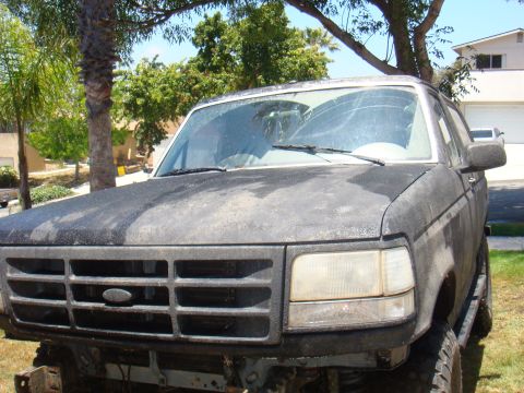 1992 Ford Bronco - Front view of a dusty 1992 Ford Bronco with a prominent grille and cracked windshield.