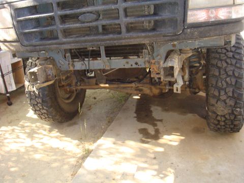 1992 Ford Bronco - Front axle and suspension components of a truck are visible, with the grille in the background.