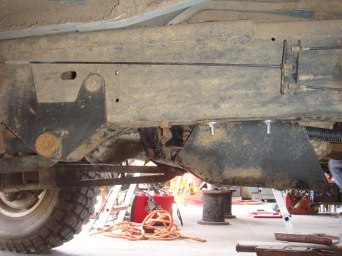 1992 Ford Bronco - The underside of a vehicle shows suspension parts and a skid plate, with a welder and other equipment visible.