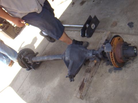 1992 Ford Bronco - A rear axle assembly with disc brakes and hub is shown on the ground, with people working around it.