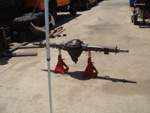 1992 Ford Bronco - Rear axle assembly supported by jack stands in an outdoor setting with other vehicles in the background.