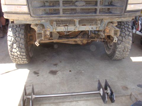1992 Ford Bronco - The front grille and axle of a 1992 Ford Bronco are visible, equipped with large off-road tires.