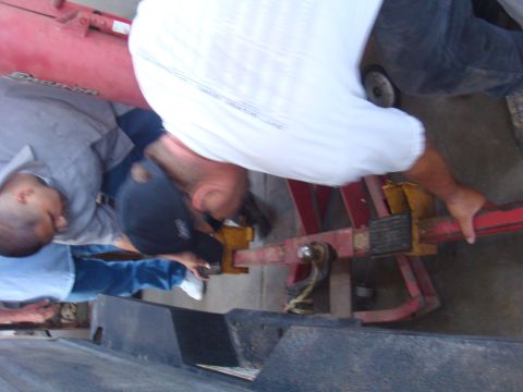 1992 Ford Bronco - People are working on a red metal vehicle part with yellow clamps.