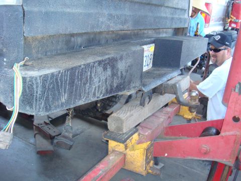 1992 Ford Bronco - A man works on the trailer hitch attached to the rear bumper of a vehicle.