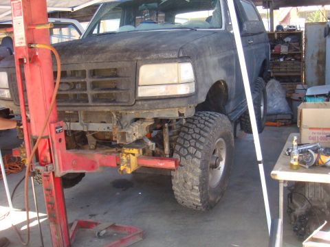 1992 Ford Bronco - A 1992 Ford Bronco is undergoing repairs in a garage, with its front end disassembled and lifted.
