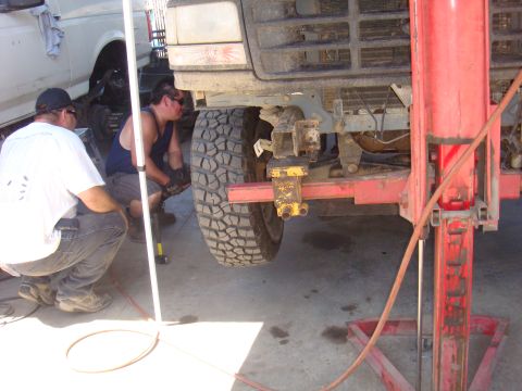 1992 Ford Bronco - Mechanics performing work on a 1992 Ford Bronco, with another vehicle in the background.