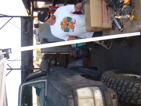1992 Ford Bronco - A man is working on a vehicle in a cluttered garage. The vehicle appears to be an older SUV with large tires.