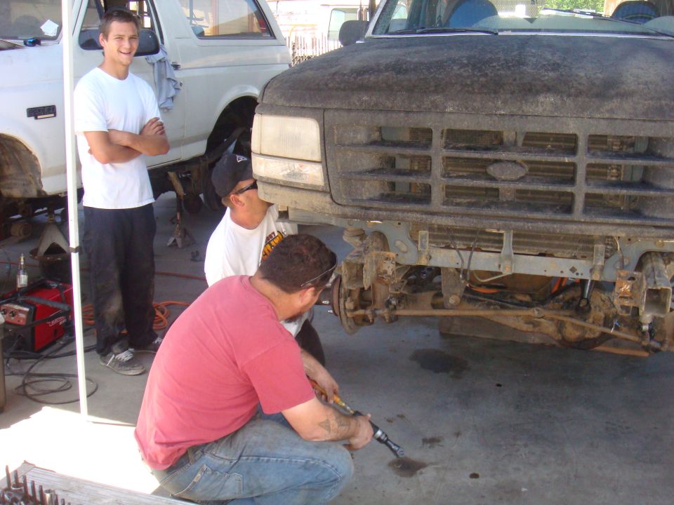 1992 Ford Bronco front end with grille and bumper removed, being worked on by mechanics