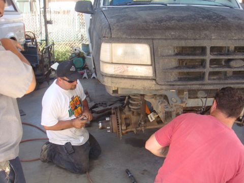 1992 Ford Bronco - Mechanics work on the front axle and suspension of a 1992 Ford Bronco during a repair.
