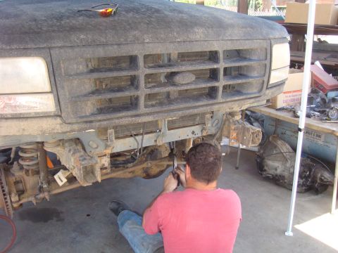 1992 Ford Bronco - A person is working on the front end of a 1992 Ford Bronco, possibly during a repair or modification.