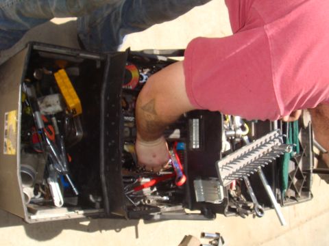 1992 Ford Bronco - A person's arm is reaching into an open toolbox overflowing with tools.