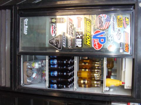 1992 Ford Bronco - Refrigerator stocked with beer and condiments, adorned with numerous automotive-themed stickers.
