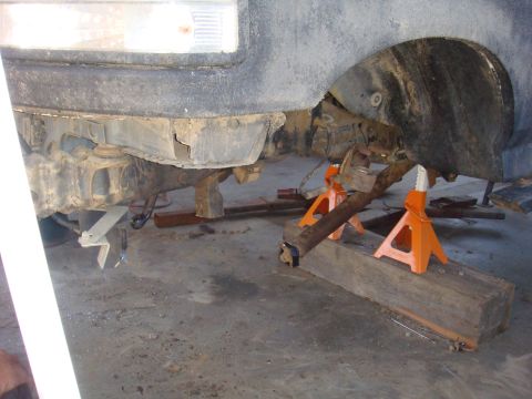 1992 Ford Bronco - The underside of a vehicle is shown raised on jack stands, with suspension and axle components visible.